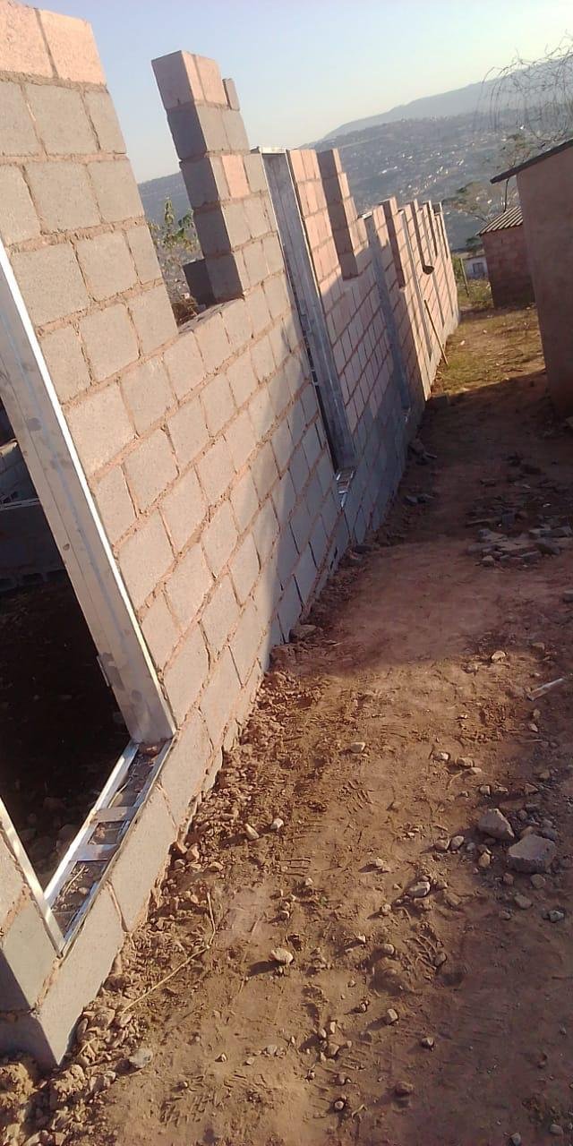Blockwork walls with steel door and window frames being built on a hillside site